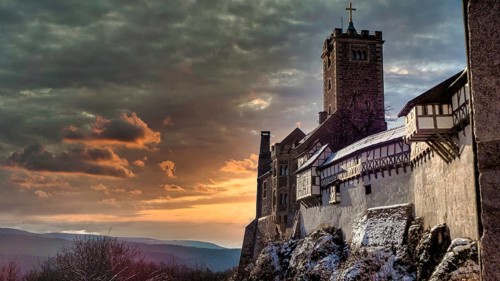 Snowy Wartburg in Eisenach in front of a picturesque and dramatic sky in romantic colors, at dusk,