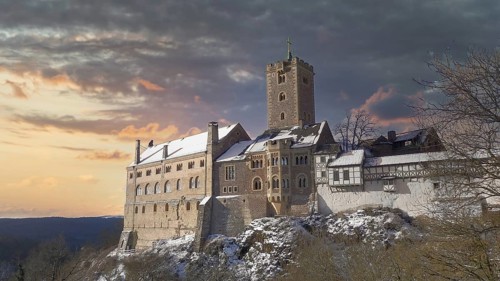 Snowy Wartburg in Eisenach in front of a picturesque and dramatic sky in romantic colors, at dusk,