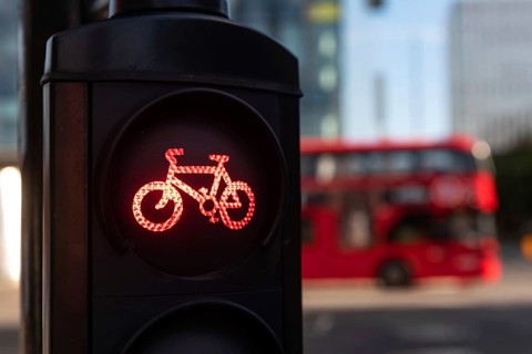 A red cycle lane traffic stop signal at a junction in a busy London city street with a double