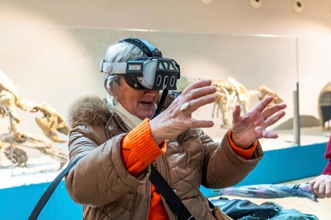 Senior woman wearing a vr headset reaching out with her hands, interacting with a virtual