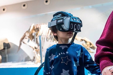 Young boy wearing a virtual reality headset, exploring an immersive experience at a museum with a
