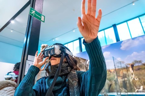 Woman wearing vr goggles, using hand gestures to interact with an immersive digital experience