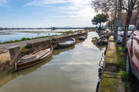 Traditional boats moored along a narrow canal in el palmar fishing village, reflecting the sky and