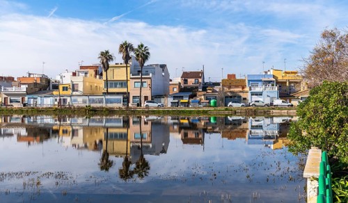 El palmar fishing village houses and palm trees mirrored in the calm albufera lake under a vivid