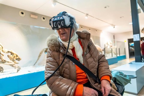 Senior woman wearing a vr headset, experiencing an immersive virtual reality exhibition in a modern