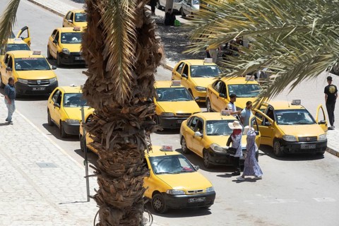 Streets of Sfax busy with taxi cabs waiting outside ancient fortified gate of Sfax Medina, known as