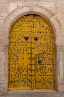 Detailed yellow ornate design of a typical door in the Medina of Tunis, a UNESCO designated quarter
