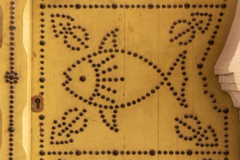 Distinctive fish design, an architectural detail of a traditional yellow painted door in the Medina