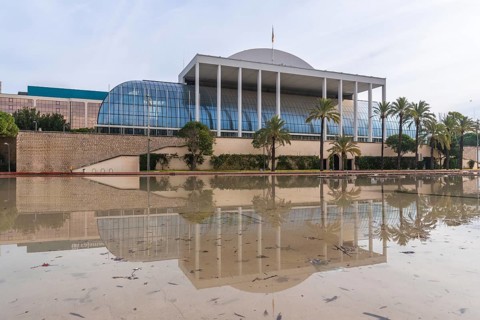 The palau de la musica music hall in valencia, spain, reflecting in a large permanent water feature