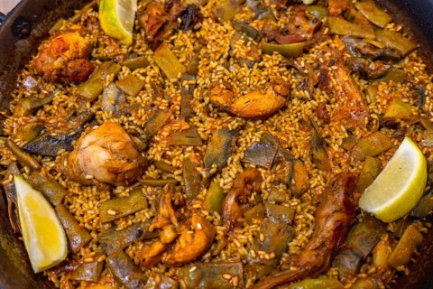 Authentic valencia paella cooking in a wide shallow pan, showcasing flavorful rice, seasoned