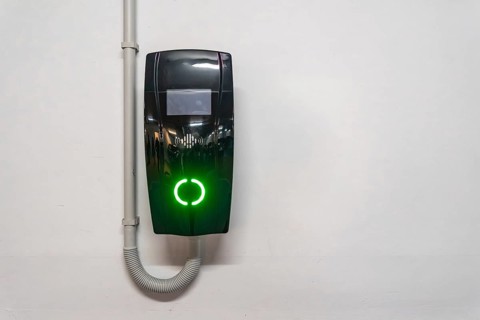 Electric vehicle wallbox charger mounted on a white wall in valencia, spain, glowing bright green