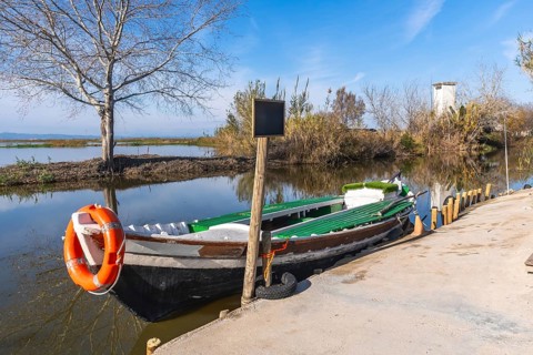 Traditional fishing boat with an orange lifebuoy tied to its bow, moored at a concrete dock beside