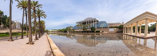 Palau de la musica concert hall architecture reflecting in a calm water pond, surrounded by palm