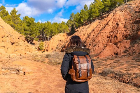Woman with a backpack exploring the scenic red clay canyons and erosion features of las arcillas