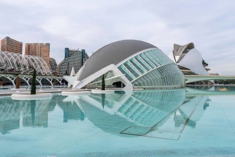 Hemisferic building reflecting in turquoise lagoon at the city of arts and sciences in valencia,