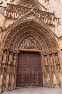 Valencia cathedral's door of the apostles displaying intricate gothic stone carvings. Religious