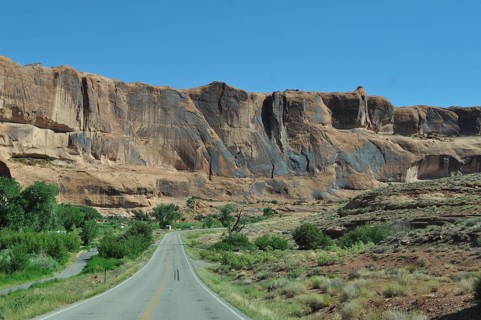 Road leads through an impressive desert landscape with high rock walls, Canyonlands National Park,
