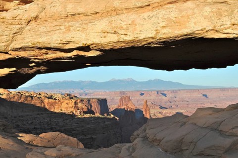 Natural Mesa Arch rock arch with views of mountains and canyon landscape, Canyonlands National