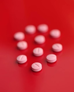 A striking image featuring several pink tablets casually dispersed on a saturated red backdrop,