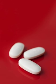 A minimalist image featuring three oblong white tablets, subtly embossed, isolated against a deep