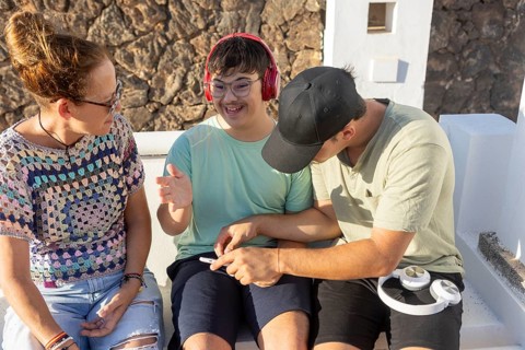 A teenager with Down Syndrome smiling and enjoying music with family The group interacts warmly,