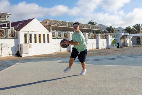 A Down syndrome teenager actively participates in a lively basketball game, This heartwarming scene