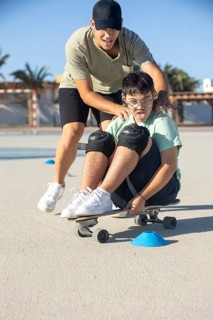 Down syndrome teenager skateboarding with his brother, enjoying an outdoor sports activity together