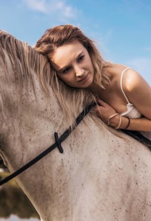 A serene scene of a young woman gently resting her head against a horse, conveying a deep