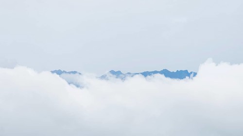 Ethereal view of jagged mountain peaks peering through a blanket of white clouds in San Ramon,