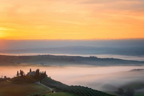 A breathtaking sunrise over the rolling hills of Val d Orcia, Tuscany, with a traditional farmhouse