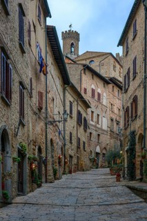 A charming cobblestone street in Volterra, Tuscany, lined with traditional stone houses adorned
