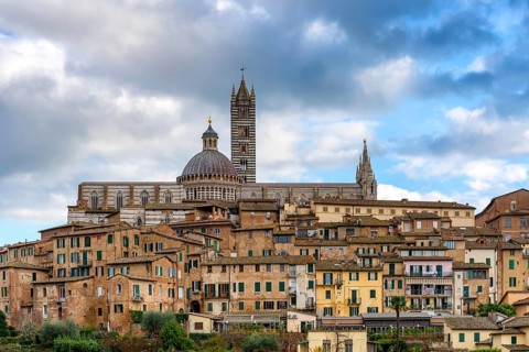 A detailed view of the Siena Cathedral rising above charming historic buildings. The Duomo's
