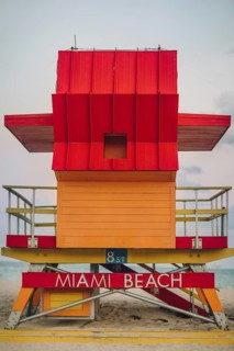 Vibrant red and orange lifeguard stand prominently positioned on Miami Beach, captured during a