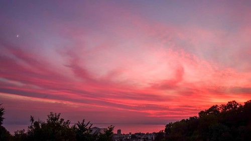 Captivating view of a vivid sunset painting the skies in shades of pink and red, over Lausanne and