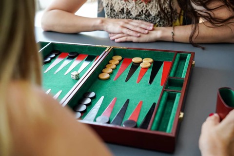 Close-up of a backgammon board with pieces and dice in play Mother and daughter are engaged in a