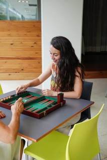 Mother and daughter are playing backgammon inside a cozy room The board is set on a table, and they