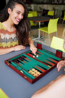 Mother and daughter engaged in a friendly game of backgammon at a cafe, The vibrant setting adds