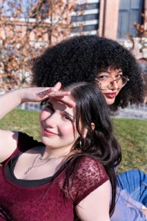 Two Gen Z friends, one Hispanic girl with curly hair and another girl with straight black hair,