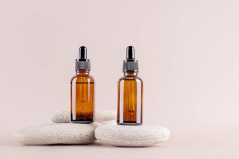 Two amber glass dropper bottles on minimalist stones, set against a neutral background Ideal for
