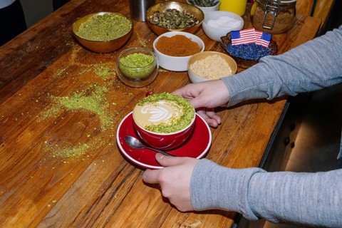 A delightful cup of specialty coffee crafted with intricate pistachio latte art on a wooden table.