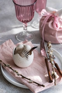 Soft pastel pink easter table setting decor. A white ceramic egg holder, adorned with subtle