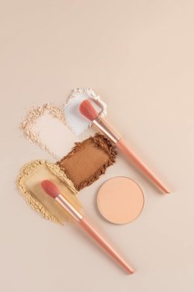 Top view of compact and loose powders with makeup brushes on a neutral background. This shot