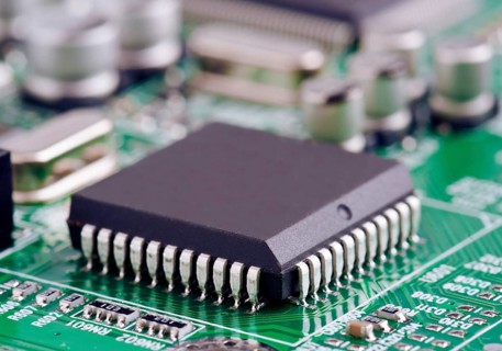 A detailed macro shot of a microchip securely mounted on a green printed circuit board,