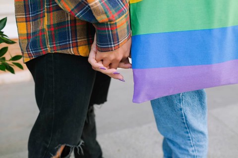 A close-up of a lesbian couple gently holding hands, symbolizing love and unity. One partner