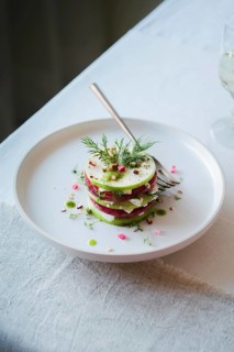 Top view of a colorful gourmet salad stacked with alternating slices of radish and cucumber,