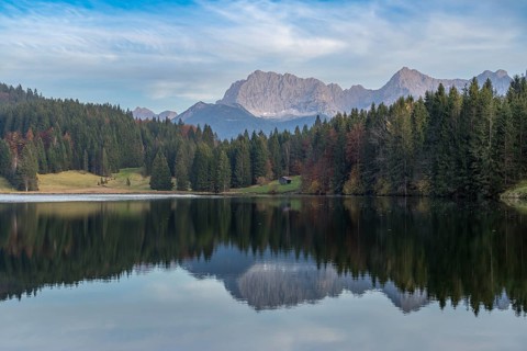 Tranquil Geroldsee with the stunning Bavarian Alps in the background Tall evergreens and rocky