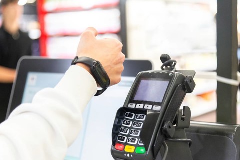 Cropped image of woman's hand making a payment using a smartwatch at a card terminal in a