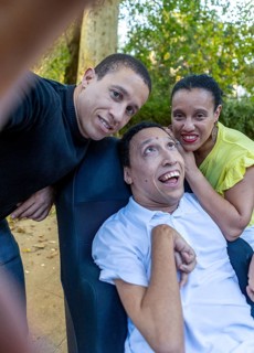 Spanish Cameroonian siblings sharing a joyful moment outdoors. One sibling has cerebral palsy. This