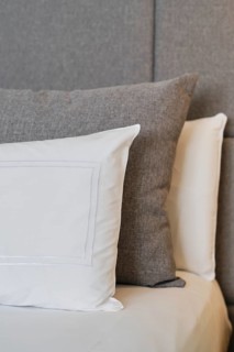 A close-up of a hotel room showcasing neatly arranged pillows on a textured headboard, highlighting