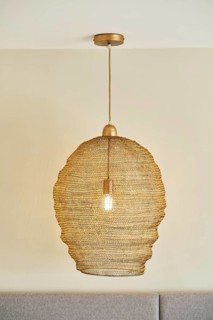 A stylish woven pendant light hangs from a hotel room ceiling, casting a warm glow. The beige color